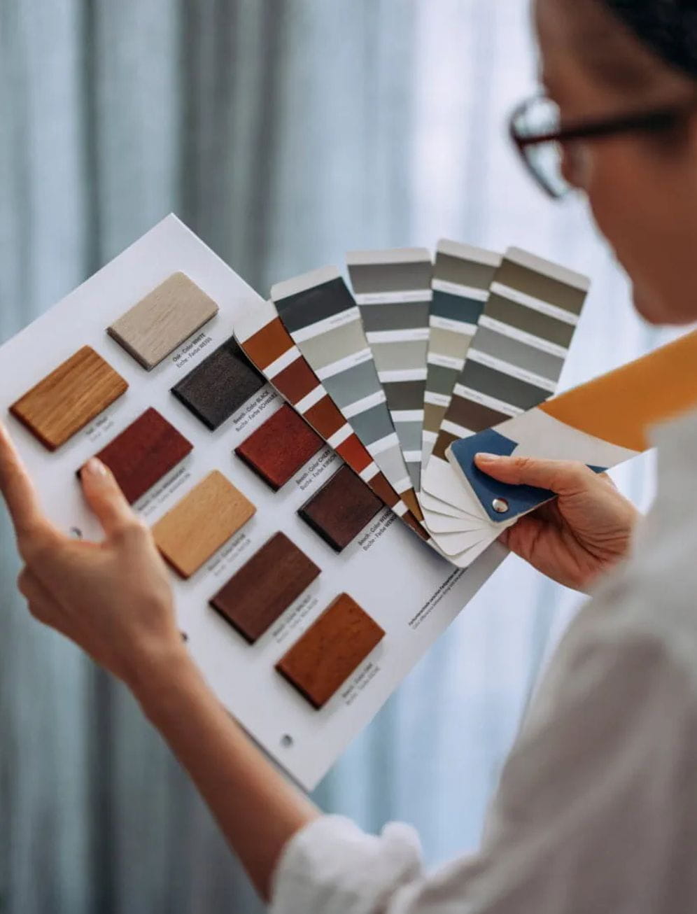 Uma mulher a analisar amostras de materiais e uma paleta de cores para remodelação de habitação, cenário associado ao planeamento de obras, personalização da casa e procura de soluções de crédito habitação para financiar renovações e melhorias do imóvel.