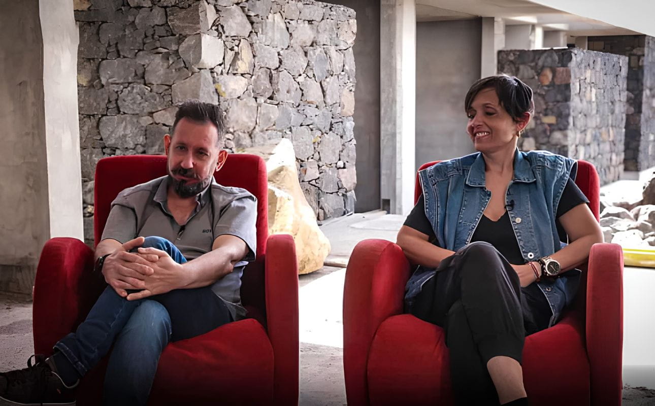 Um casal sentado em dois cadeirões vermelhos no interior de um edifício em construção, cenário associado a testemunhos reais de clientes e à experiência de construir ou renovar casa com o apoio da UCI.